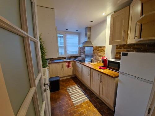 une cuisine avec des armoires en bois et un réfrigérateur blanc dans l'établissement Appartement Lumineux Caen, à Caen