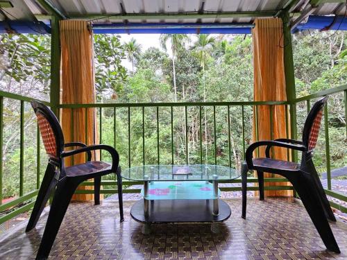 a balcony with a glass table and two chairs at Bamboo leaf Homestay in Meppādi