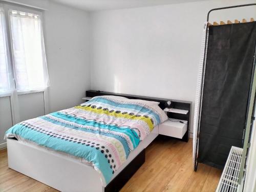 - une chambre avec un lit et une couverture colorée dans l'établissement appartement en plein coeur de ville, à Lannion
