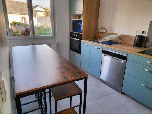 une cuisine avec des placards bleus et une table en bois dans l'établissement appartement en plein coeur de ville, à Lannion