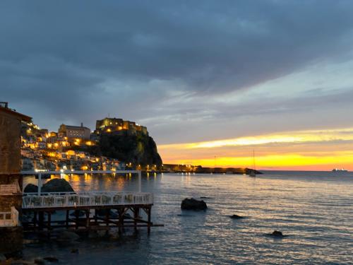 a dock in the water with a sunset in the background at Leonardo Suites Scilla in Scilla