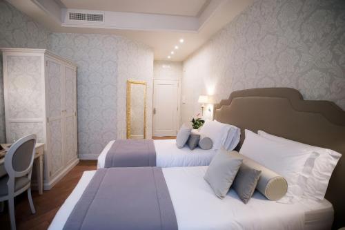 a bedroom with two beds with white pillows and a desk at San Gemini Palace in San Gemini