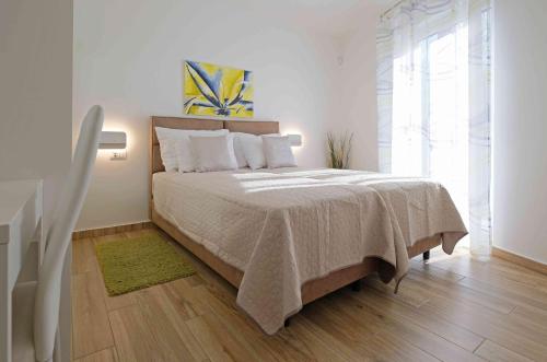 a white bedroom with a large bed with a green rug at Villa Dobranka in Barban