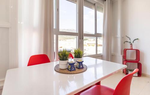 トレモリノスにあるGorgeous Apartment In Torremolinosのダイニングルーム(白いテーブル、赤い椅子付)