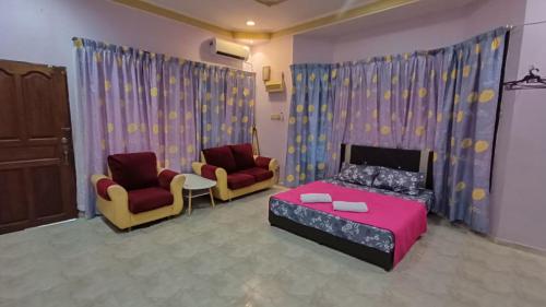 a bedroom with a bed and two chairs in a room at Homestay Segamat - Teratak Impian in Segamat
