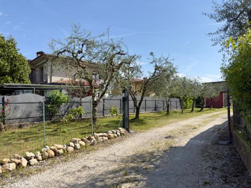 a dirt road with a fence and trees and a house at B&B LA CORTE in Puegnano del Garda