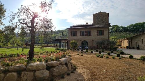 a building with a stone wall in front of a garden at La Torre sulla via Francigena in Gambassi Terme