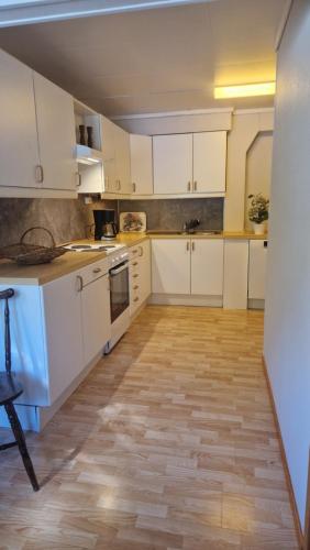 a kitchen with white cabinets and a wooden floor at Kvamsdal Pensjonat in Eidfjord