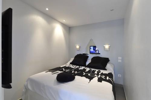 - une chambre avec un grand lit et des oreillers noirs dans l'établissement Appartement NEW YORK - Héliopolis O15 - Luxe - 2 personnes, au Cap d'Agde