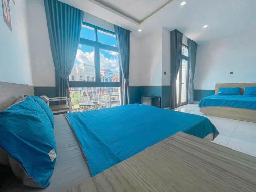 a bedroom with two beds and a large window at Mila Homstay in Phú Quốc