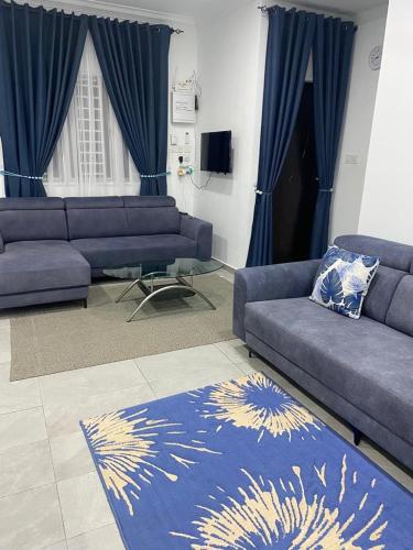 a living room with two couches and a rug at IDAMAN COTTAGE Sekinchan in Tanjung Karang