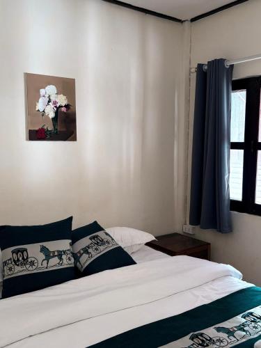 a bedroom with a bed and a vase of flowers at Manotemple Guest House in Luang Prabang