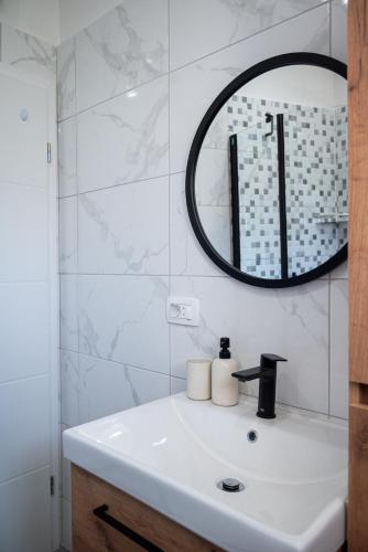 a white bathroom with a sink and a mirror at Apartman Tarja in Kastel Novi