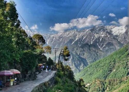 a view of a mountain with people walking down a road at Feel at Home Tranquil trails home stay naddi in Dharamshala