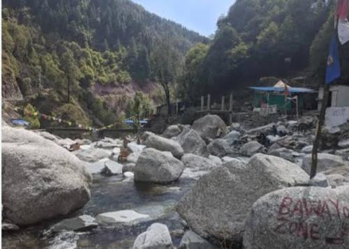 a river with rocks in the middle of a mountain at Feel at Home Tranquil trails home stay naddi in Dharamshala
