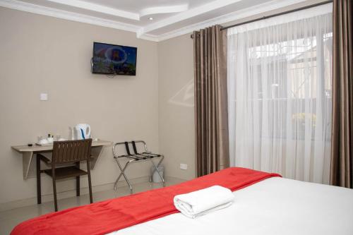una camera da letto con un letto, una scrivania e una finestra di Ivory Inn Bed & Breakfast a Gaborone