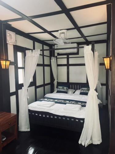 a bedroom with a bed with curtains on it at Manotemple Guest House in Luang Prabang
