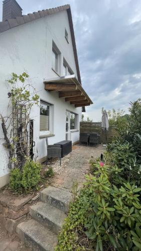 a white house with a patio and some bushes at Ferienhaus An der Weinrebe in Bad Hersfeld mit Garten, 2 Bäder, 2 Schlafzimmer & Küche - gratis Parkplätze in Bad Hersfeld