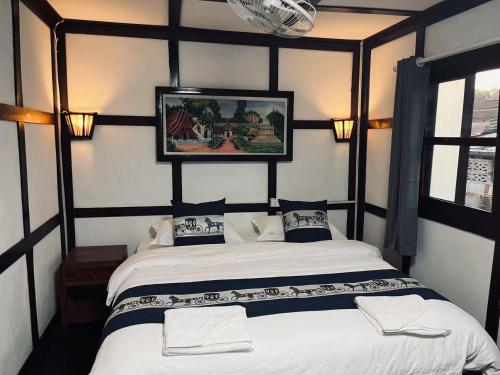 a bedroom with a bed and a picture on the wall at Manotemple Guest House in Luang Prabang