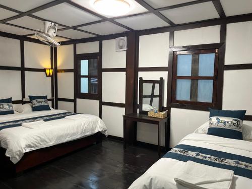 a room with two beds and a mirror in it at Manotemple Guest House in Luang Prabang