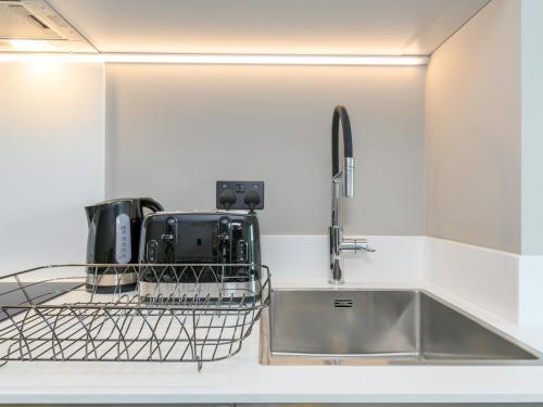 a kitchen with a sink and a dish drying rack at Amazing Views in Central Leeds - Pass The Keys in Leeds