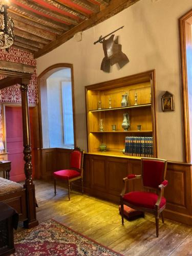 a bedroom with two chairs and a shelf with books at Le Logis d'Equilly in Équilly