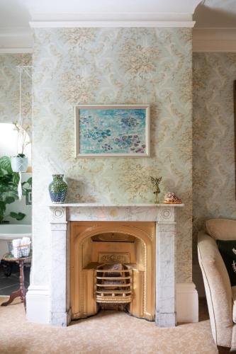 a fireplace in a living room with a painting on the wall at Enchanted Manor in Niton