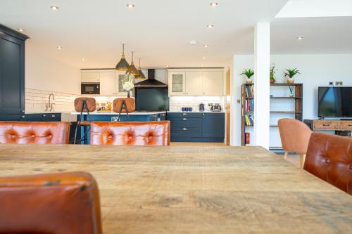 a kitchen with a large wooden table and orange chairs at Beautiful Barn Conversion - Orchard Escape for 12! in Cropthorne