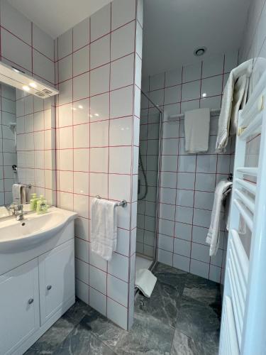 La salle de bains est pourvue d'un lavabo et d'une douche avec du carrelage rose. dans l'établissement Gîte chez Marie-Sarah petite maison calme parking, à Ebersheim