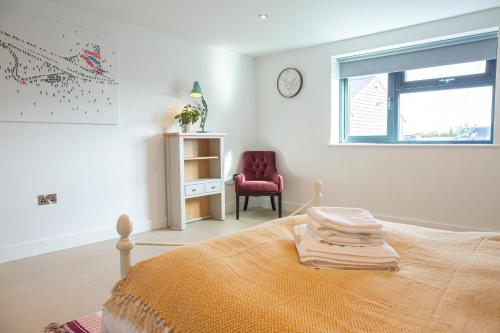 a bedroom with a bed and a chair and a window at Beautiful Barn Conversion - Orchard Escape for 12! in Cropthorne