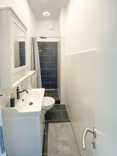 a white bathroom with a sink and a shower at MöwenKoje - Zentral mit PrivatParkplatz in Bremerhaven