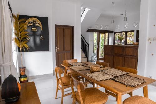 une salle à manger avec une table et des chaises en bois dans l'établissement The Light House Villa in Ubud, à Ubud