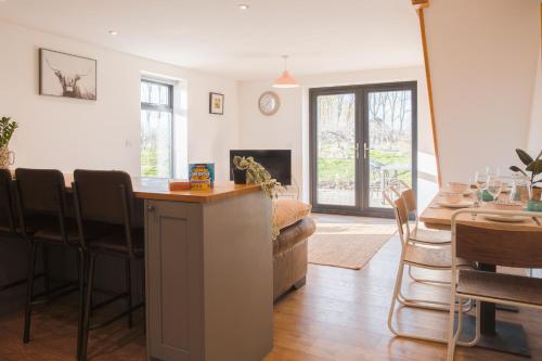 a living room with a kitchen and a dining room at Beautiful Barn Conversion - Orchard Escape for 12! in Cropthorne
