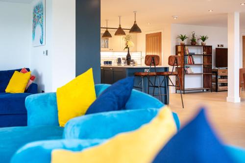 a blue couch with yellow pillows in a living room at Beautiful Barn Conversion - Orchard Escape for 12! in Cropthorne