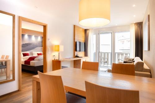 a living room with a dining room table and a bed at Apartments Crown Andermatt in Andermatt