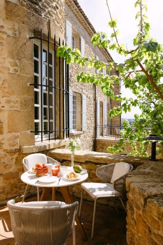 un patio extérieur avec une table et des chaises dans l'établissement Le Prieuré, à Châteauneuf-du-Pape