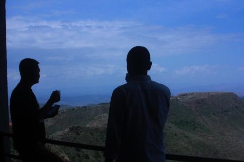 two men standing on a balcony looking out at the mountains at Halle Hotel - Lalibela in Lalībela