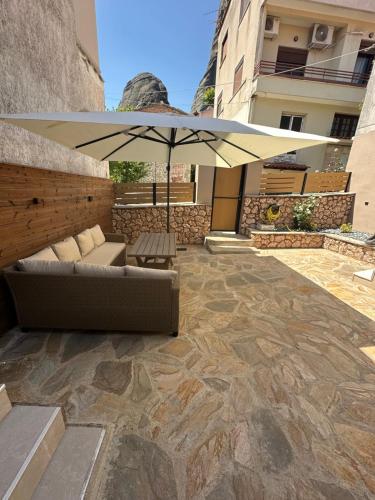 a patio with a couch and an umbrella at Villa KONTOULIS in Kalabaka
