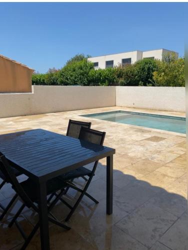 - une table et des chaises à côté de la piscine dans l'établissement Immense villa avec piscine, à Vergèze
