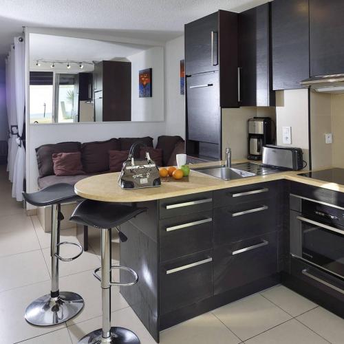 - une cuisine avec un évier et un comptoir avec une table dans l'établissement Appartement MALIBU - Héliopolis O14 - Luxe - 2 personnes, au Cap d'Agde