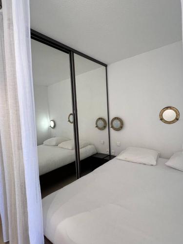 une chambre avec deux lits et un grand miroir dans l'établissement Appartement MALIBU - Héliopolis O14 - Luxe - 2 personnes, au Cap d'Agde