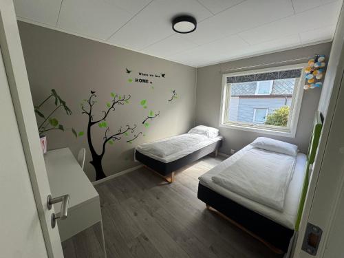 une chambre d'hôpital avec deux lits et une fresque d'arbre dans l'établissement Ålesund sentrum apartment, à Ålesund