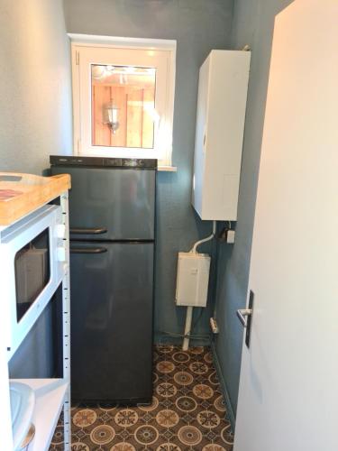 a kitchen with a black refrigerator and a window at Endeholzer Fuchsbau in Eschede
