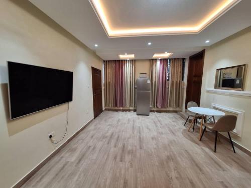 a room with a flat screen tv and a table and chairs at COD Haven Ventures Apartments in Madina
