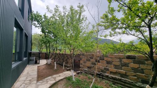 a brick wall with trees next to a building at Chill out Zone , villa with 4 bedrooms, whole apartment, апартамент целиком in Dilijan