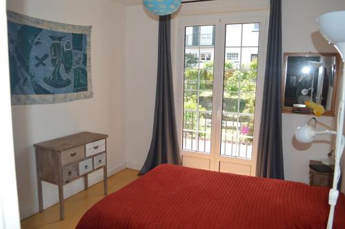 - une chambre avec un lit rouge et une fenêtre dans l'établissement A l'ombre du palmier, maison à 1,2 km de l'océan, à Hendaye