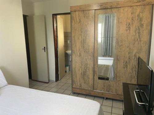a bedroom with a large wooden cabinet and a bed at Apartamento aconchegante in João Pessoa