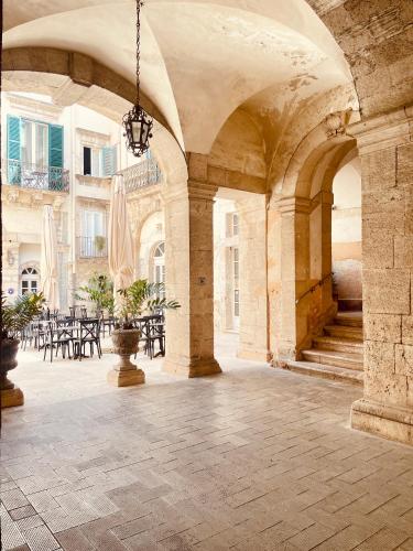 an archway with tables and chairs in a building at Loggiato Verga Luxury by Bed&Bros in Syracuse