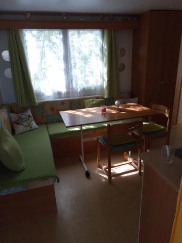 Cette chambre comprend une table, un canapé et une fenêtre. dans l'établissement Camping l'escale, à Agde