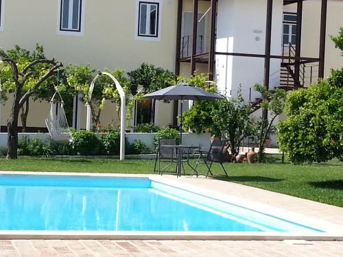 a swimming pool in front of a building with an umbrella at Casas da Moagem in São Domingos